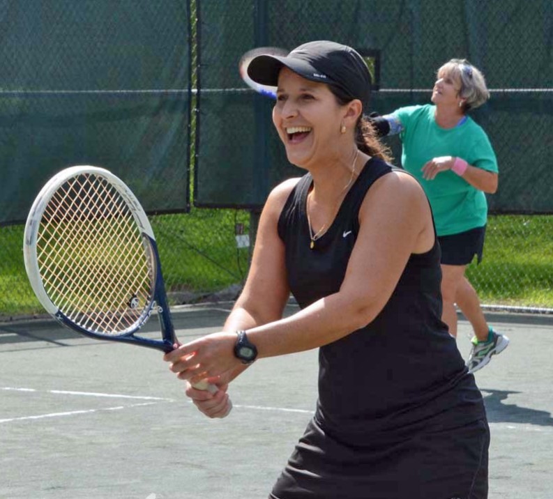 A smiling lady holding out her tennis racket